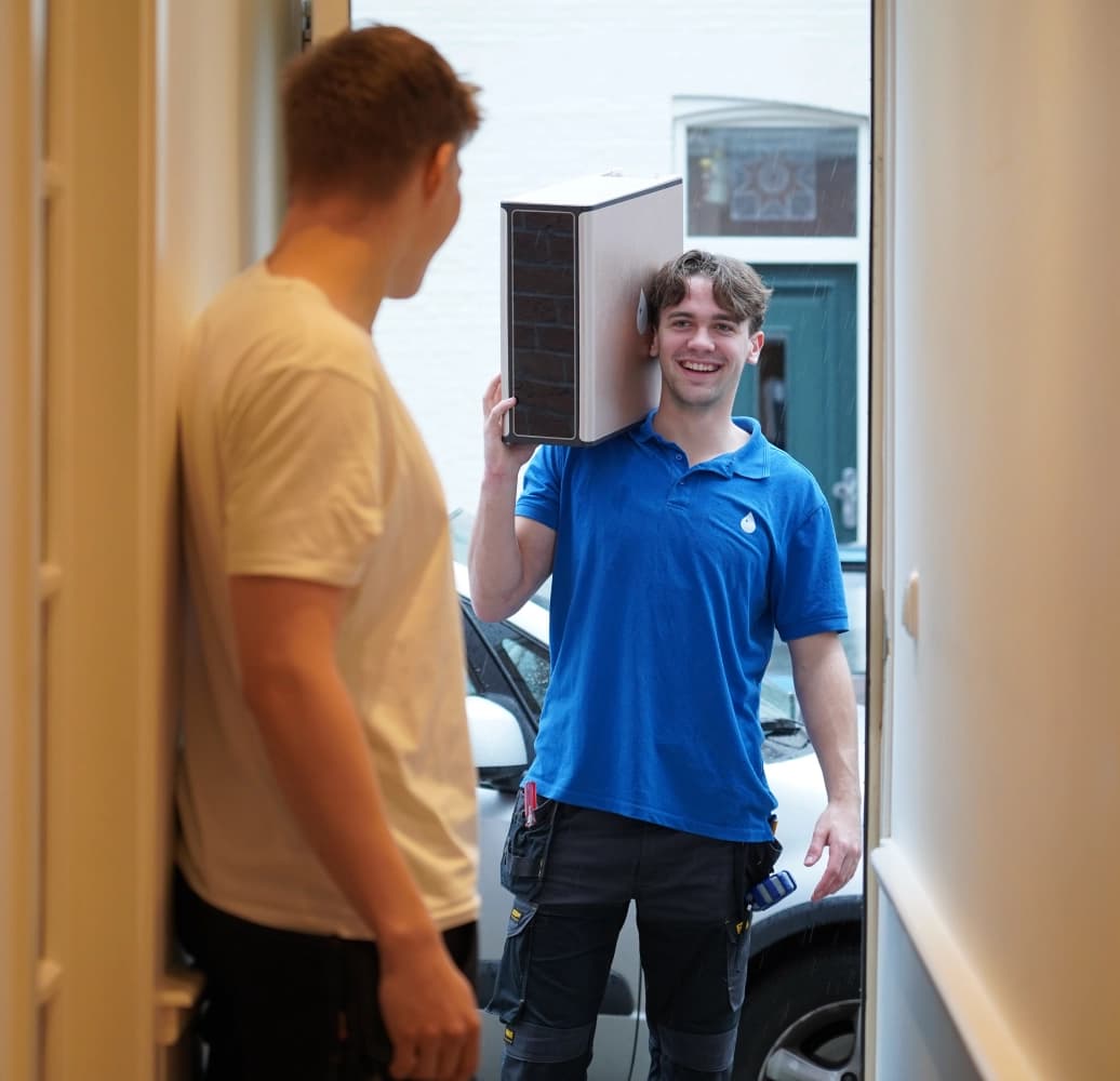 Monteur van Modern Water brengt een waterfilter bij een klant naar binnen.